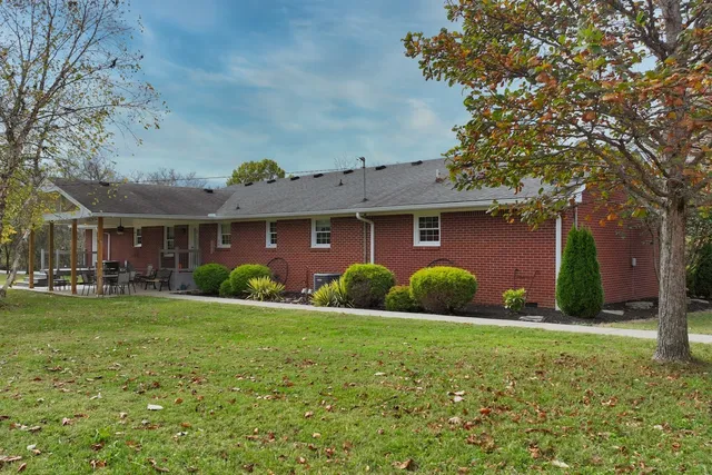 a view of a brick house with a big yard and large trees