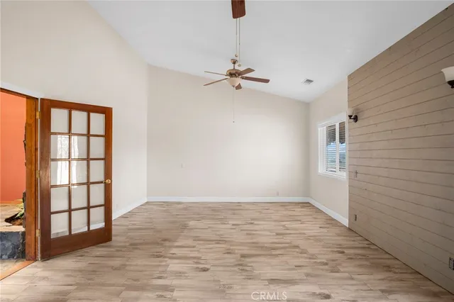 a view of empty room with wooden floor and ceiling fan