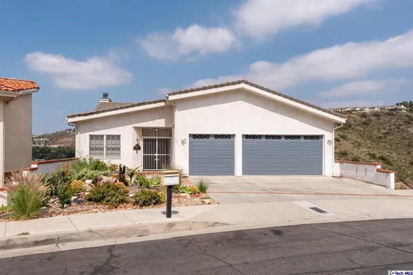 a front view of a house with a yard and potted plants