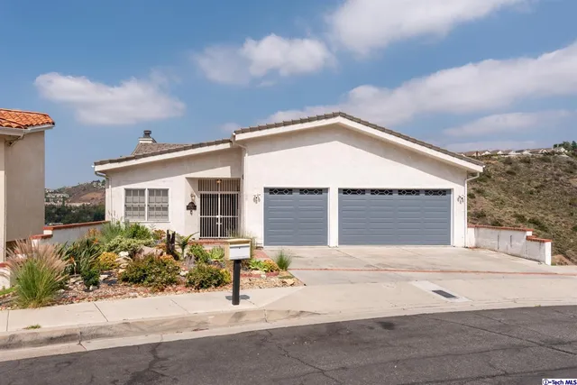 a front view of a house with a yard and potted plants
