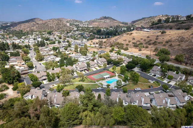 an aerial view of residential houses with outdoor space and trees