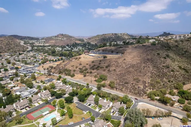 an aerial view of residential houses with outdoor space and trees