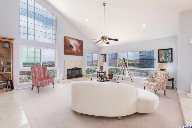 a living room with furniture a fireplace and a floor to ceiling window