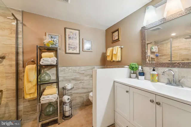a bathroom with a granite countertop mirror sink and glass door