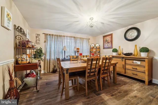 a view of a dining room and livingroom with furniture wooden floor a rug a painting and a chandelier