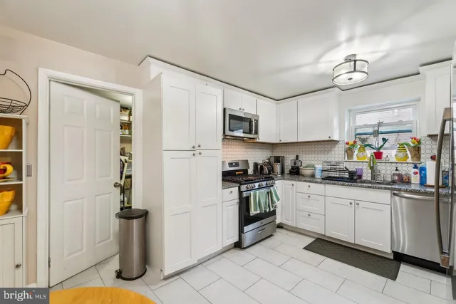 a kitchen with stainless steel appliances granite countertop a sink a stove a refrigerator a microwave oven with white cabinets