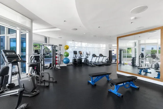 a room with lots of gym equipment and large windows