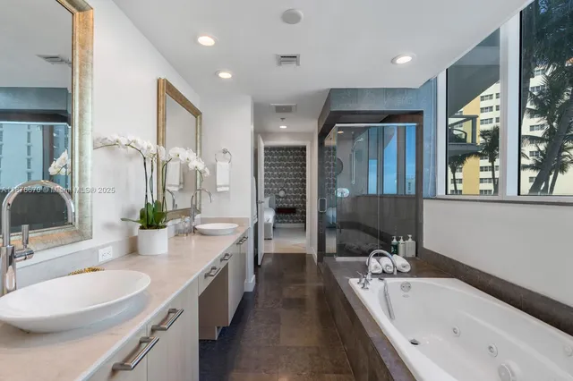 a bathroom with a granite countertop tub double vanity sink and a large mirror