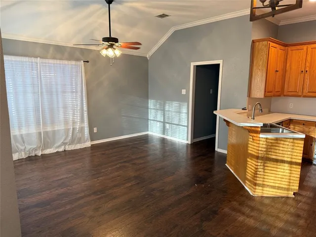 a view of empty room with wooden floor and fan