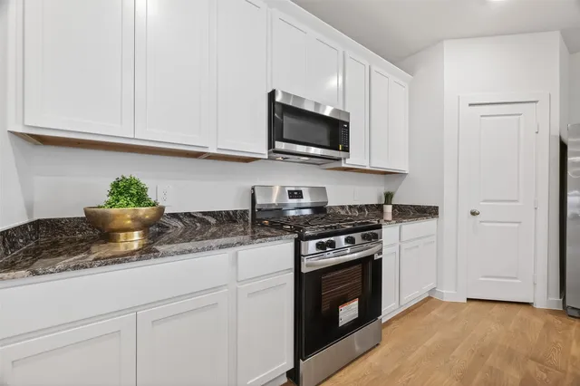 a kitchen with stainless steel appliances granite countertop white cabinets a stove top oven and sink