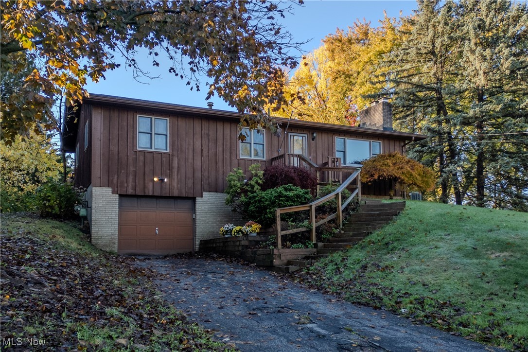 Chalet / cabin featuring stairs, brick siding, a chimney, driveway, and a garage