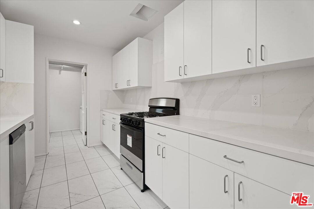 207 South Reeves Drive Beverly Hills, CA 90212 - Photo 4 of 13 a kitchen with white cabinets and appliances