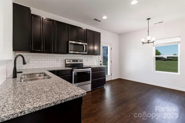 a kitchen with granite countertop stainless steel appliances a sink stove and refrigerator