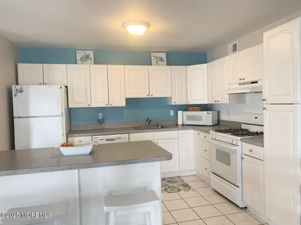 a kitchen with a sink a stove a refrigerator and white cabinets
