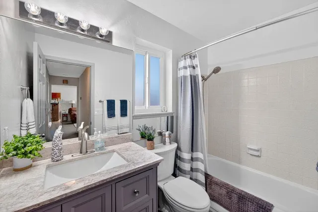 a bathroom with a granite countertop sink toilet a large mirror a shower and a bathtub