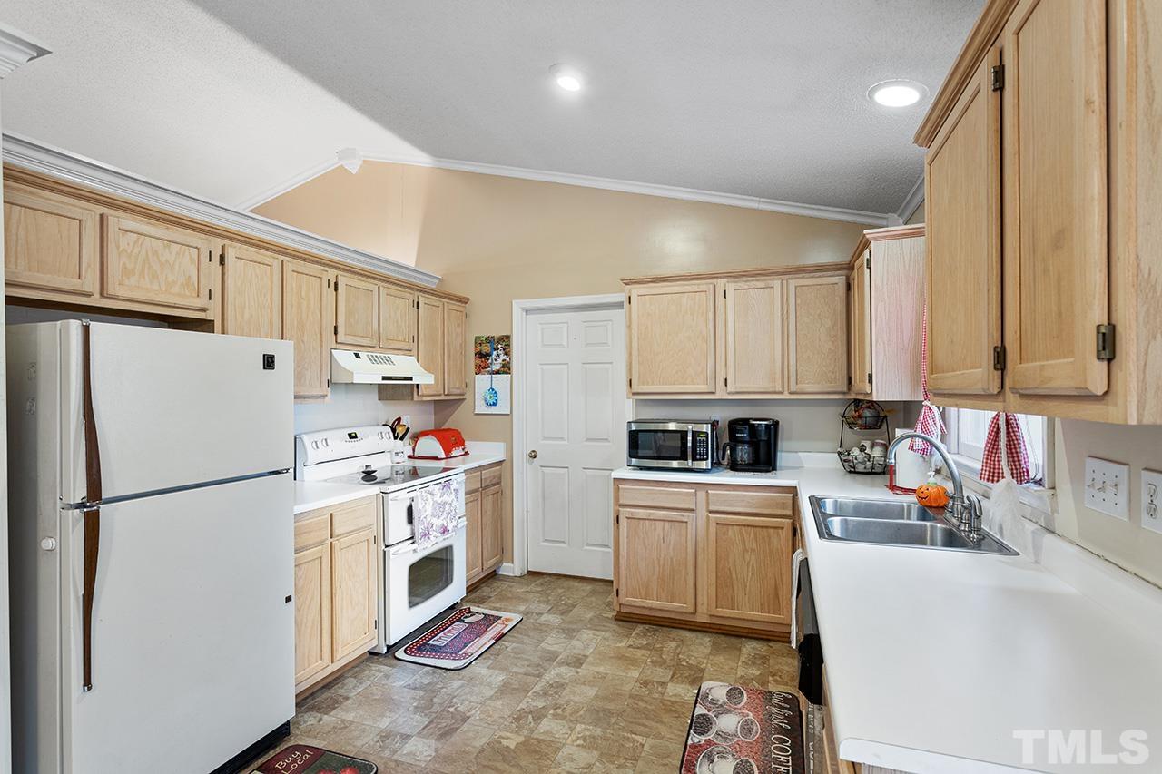 1406 Buckhorn Road Garner, NC 27529 - Photo 20 of 29 a kitchen with a refrigerator a stove top oven a sink and cabinets
