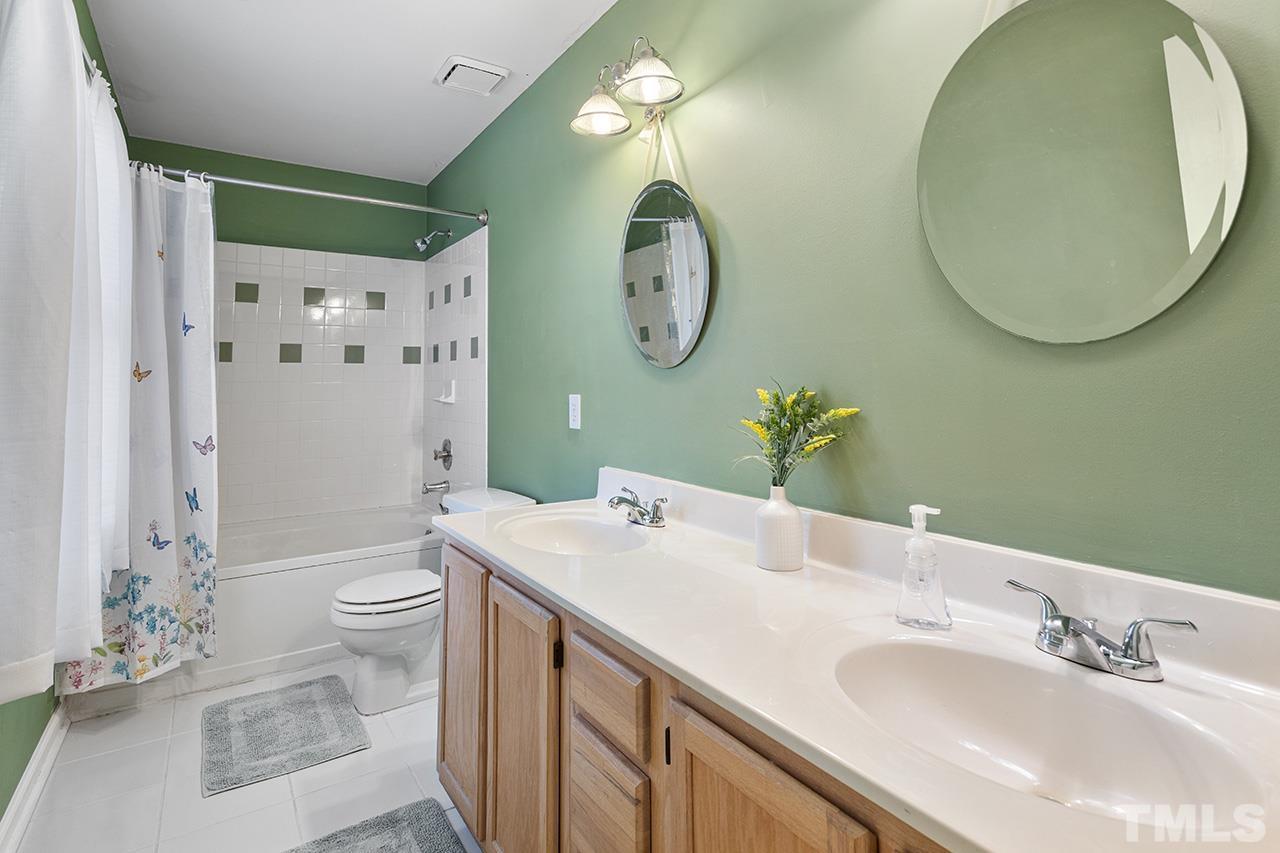1406 Buckhorn Road Garner, NC 27529 - Photo 26 of 29 a bathroom with a toilet a sink and a mirror