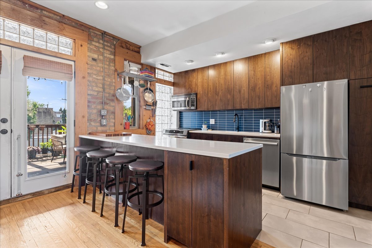 3107 West George Street, Unit 2 Chicago, IL 60618 - Photo 5 of 17 a kitchen with stainless steel appliances granite countertop a refrigerator a sink a stove and a dining table with wooden floor