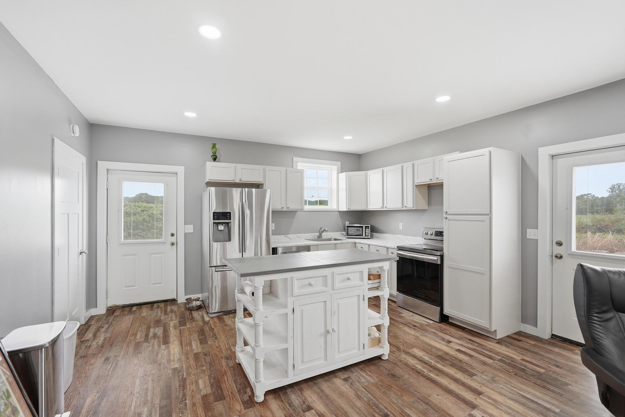 1050 Franks Ferry Road Sparta, TN 38583 - Photo 4 of 35 a kitchen with stainless steel appliances a stove top oven a refrigerator a sink and white cabinets with wooden floor