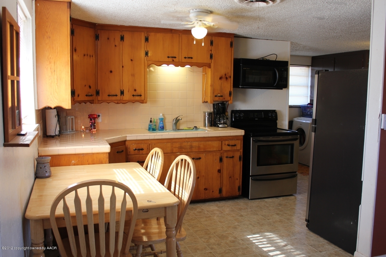 3609 Beacon Road Amarillo, TX 79118 - Photo 4 of 26 a kitchen with stainless steel appliances a kitchen island hardwood floor sink stove dining table and chairs