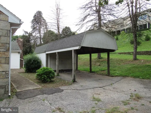 a view of a house with a yard plants and large tree