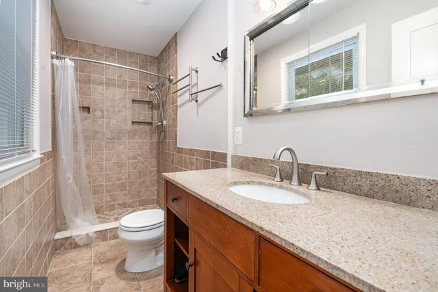 a bathroom with a granite countertop sink a mirror and a toilet