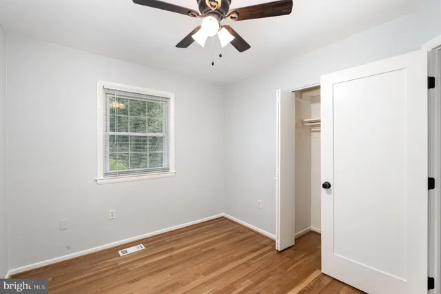 an empty room with wooden floor closet and windows