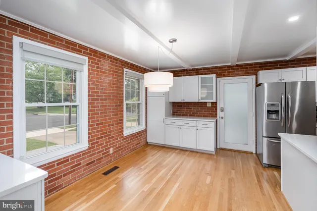 a kitchen with stainless steel appliances wooden floor and a large window