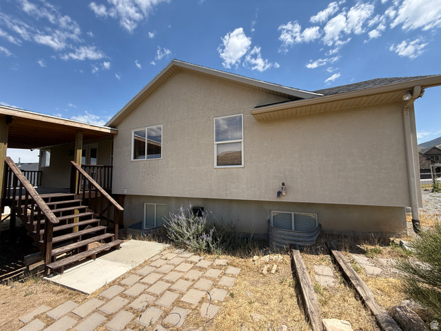 702 Elk Meadow Loop Tooele, UT 84074 - Photo 5 of 9 Exterior featuring a covered wooden deck with stairs, a stucco facade, and multiple windows