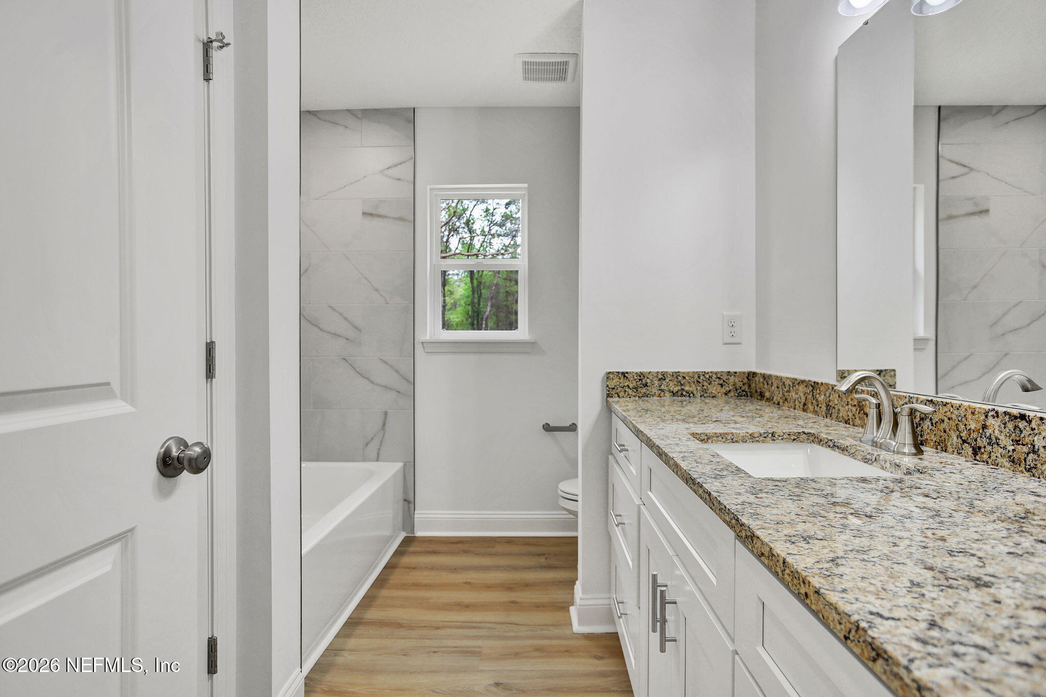 4881 Chickpea Street Middleburg, FL 32068 - Photo 16 of 19 a bathroom with a granite countertop sink a mirror and a bathtub