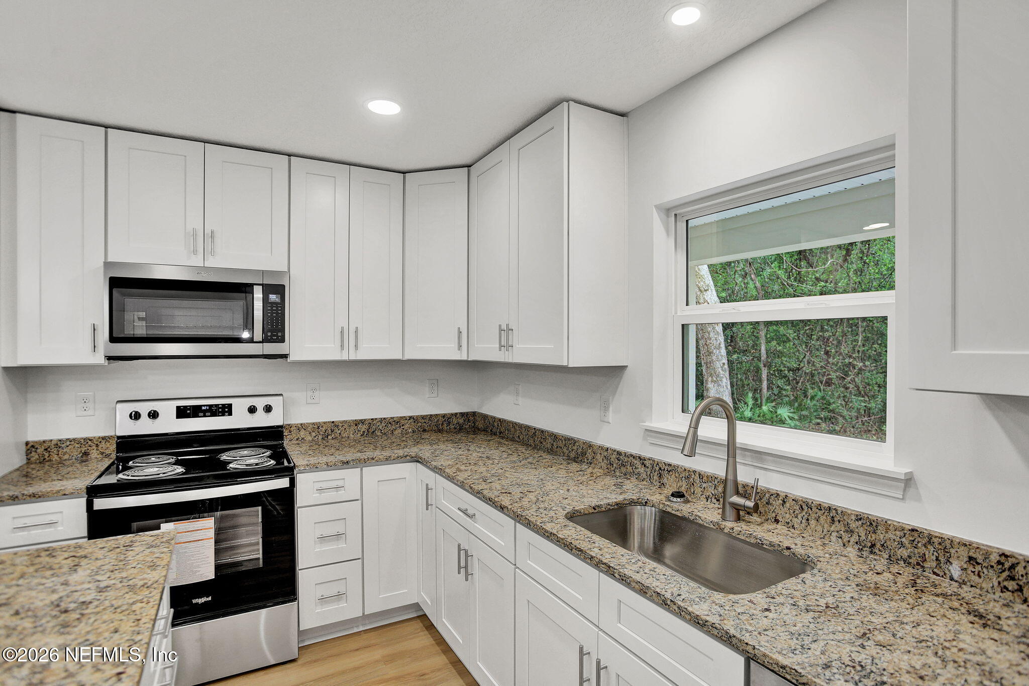 4881 Chickpea Street Middleburg, FL 32068 - Photo 3 of 19 a kitchen with granite countertop white cabinets sink and stainless steel appliances