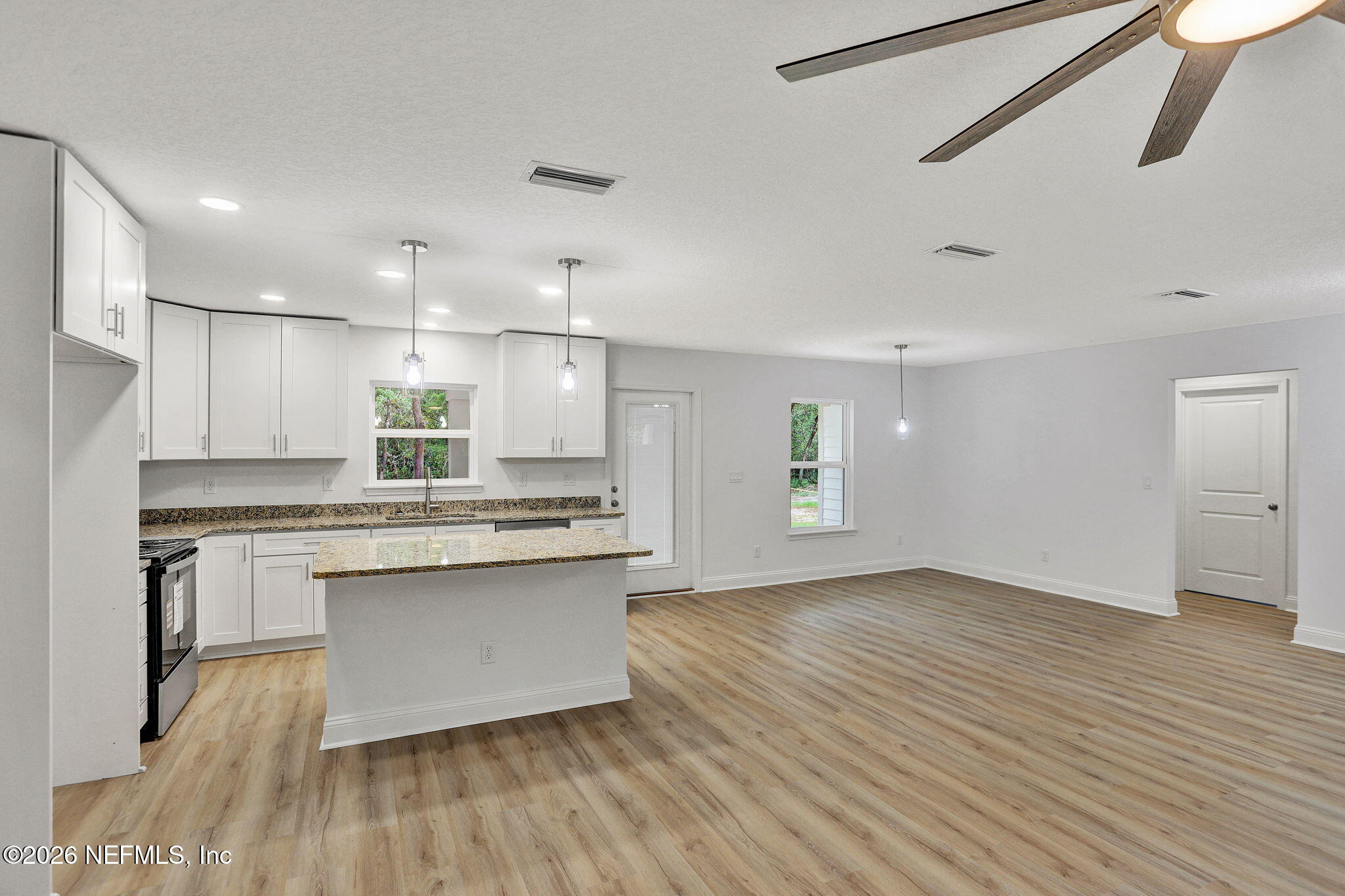 4881 Chickpea Street Middleburg, FL 32068 - Photo 5 of 19 a kitchen with kitchen island a sink dishwasher a stove and white cabinets with wooden floor