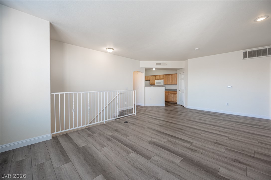8555 West Russell Road, Unit 2062 Las Vegas, NV 89113 - Photo 11 of 35 Natural light illuminates this versatile living area featuring wood plank flooring and a modern railing.