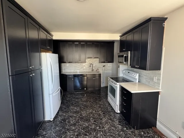 a kitchen with stainless steel appliances granite countertop a refrigerator a sink a stove and a refrigerator