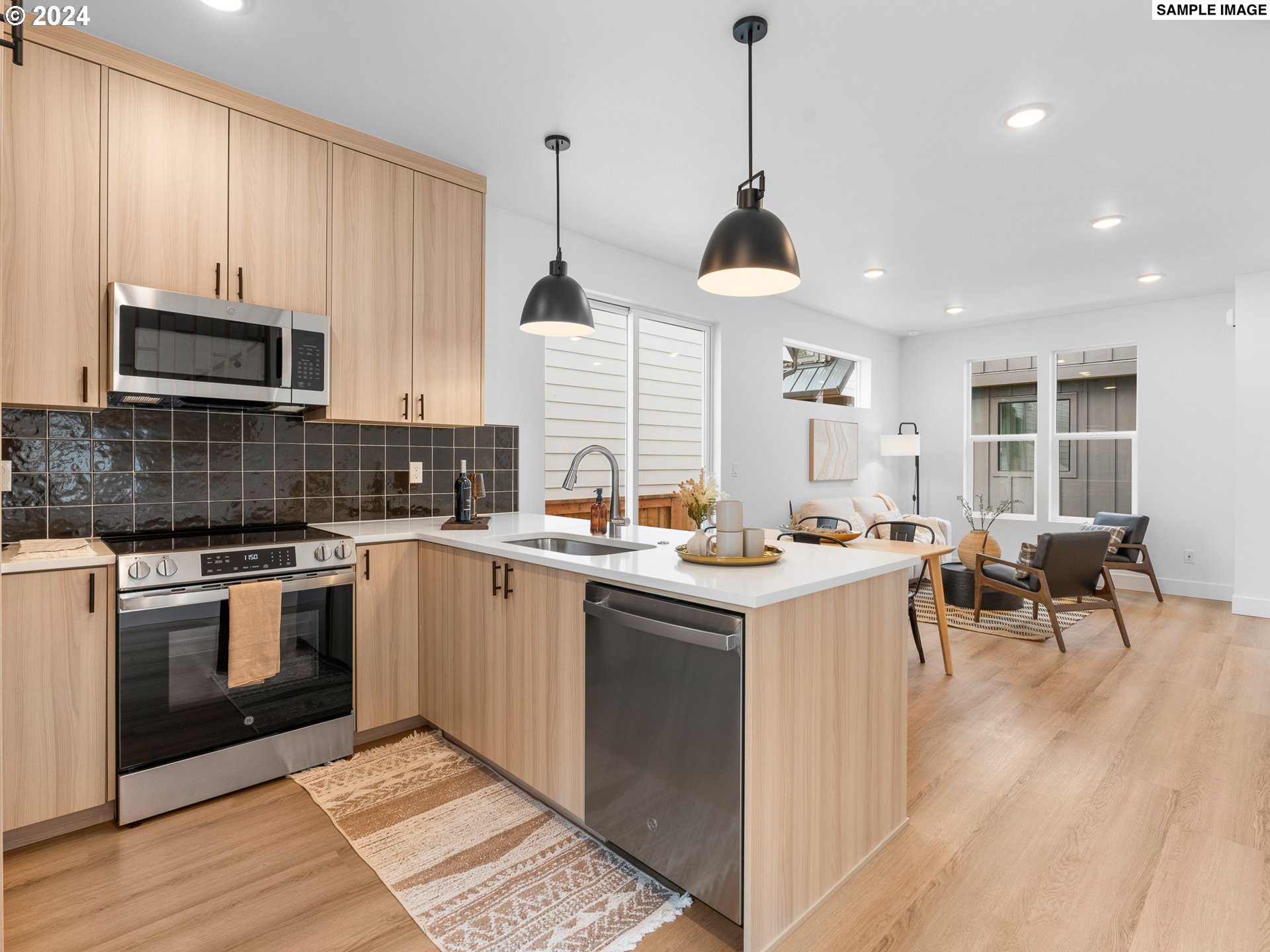 6195 North Amherst Street Portland, OR 97203 - Photo 6 of 20 a kitchen with stainless steel appliances granite countertop a sink a stove and a wooden floors