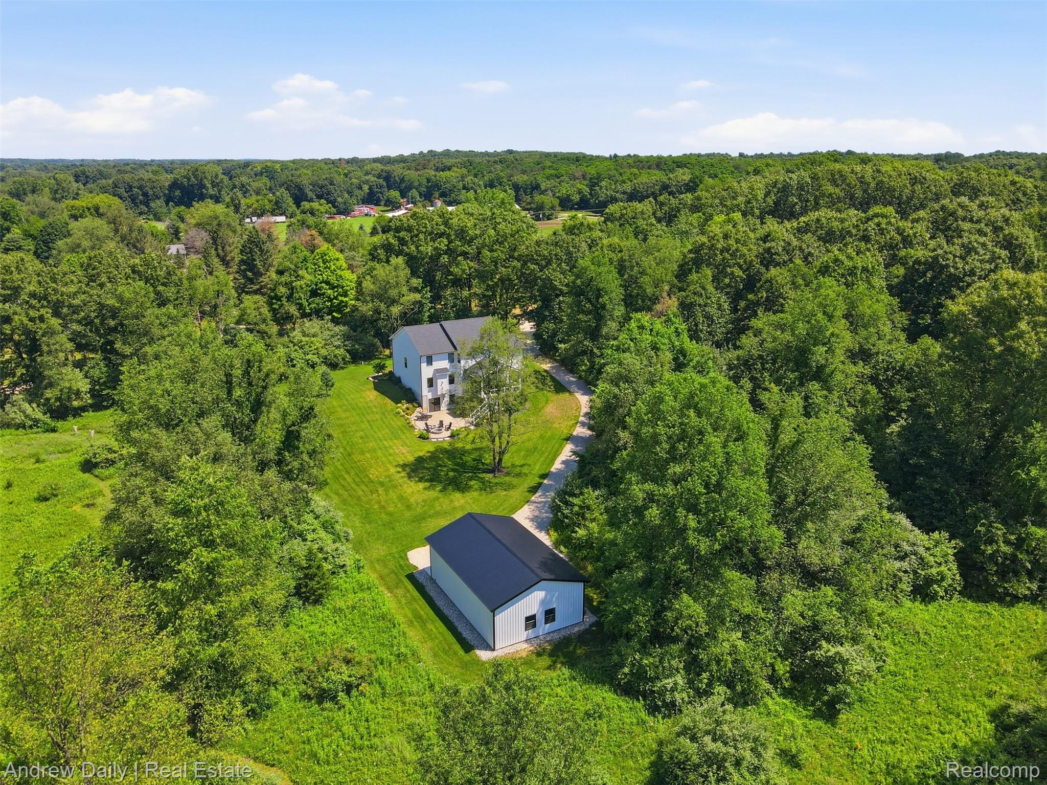 4661 Spears Road Pinckney, MI 48169 - Photo 50 of 56 Aerial perspective showcasing a light-colored multi-story residence with a dark roof, surrounded by mature trees and verdant landscaping