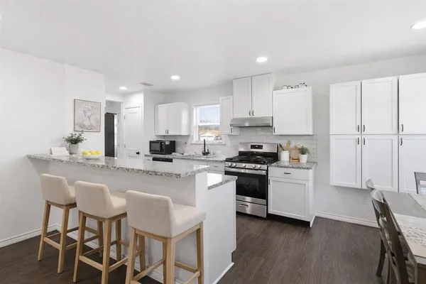 a kitchen with stainless steel appliances a sink a stove a table and chairs