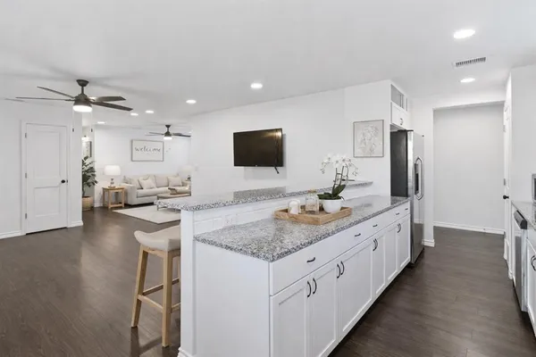 a large white kitchen with a large island oven a sink stainless steel appliances and cabinets