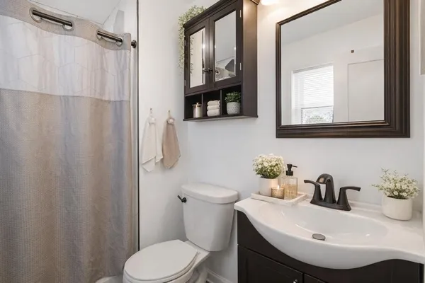 a bathroom with a sink a mirror a toilet and a window
