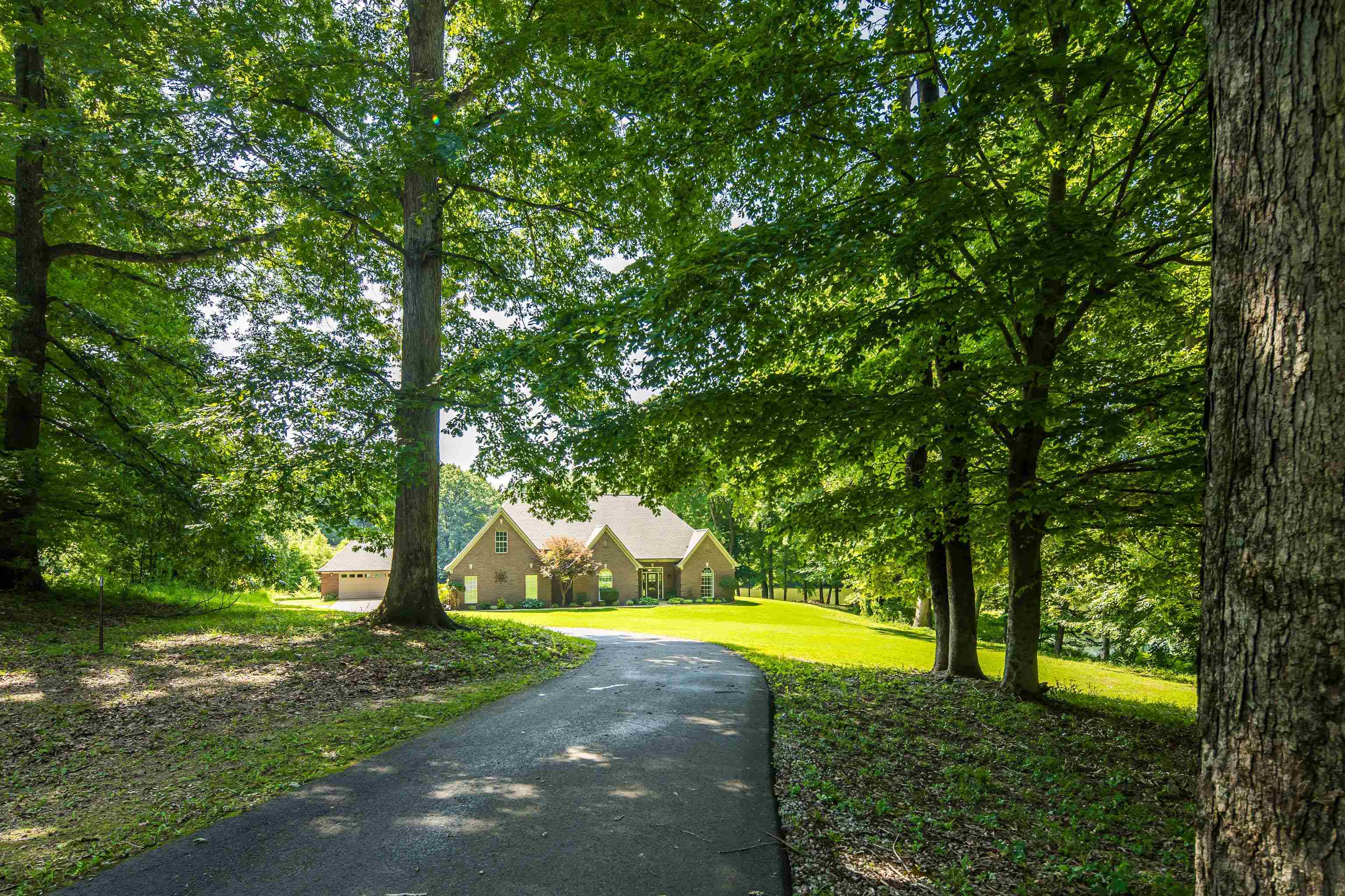 243 Hayes Road Munford, TN 38058 - Photo 1 of 25 Expansive property featuring a paved driveway, mature trees, manicured lawn, and a brick exterior residence with a multi-gabled roof