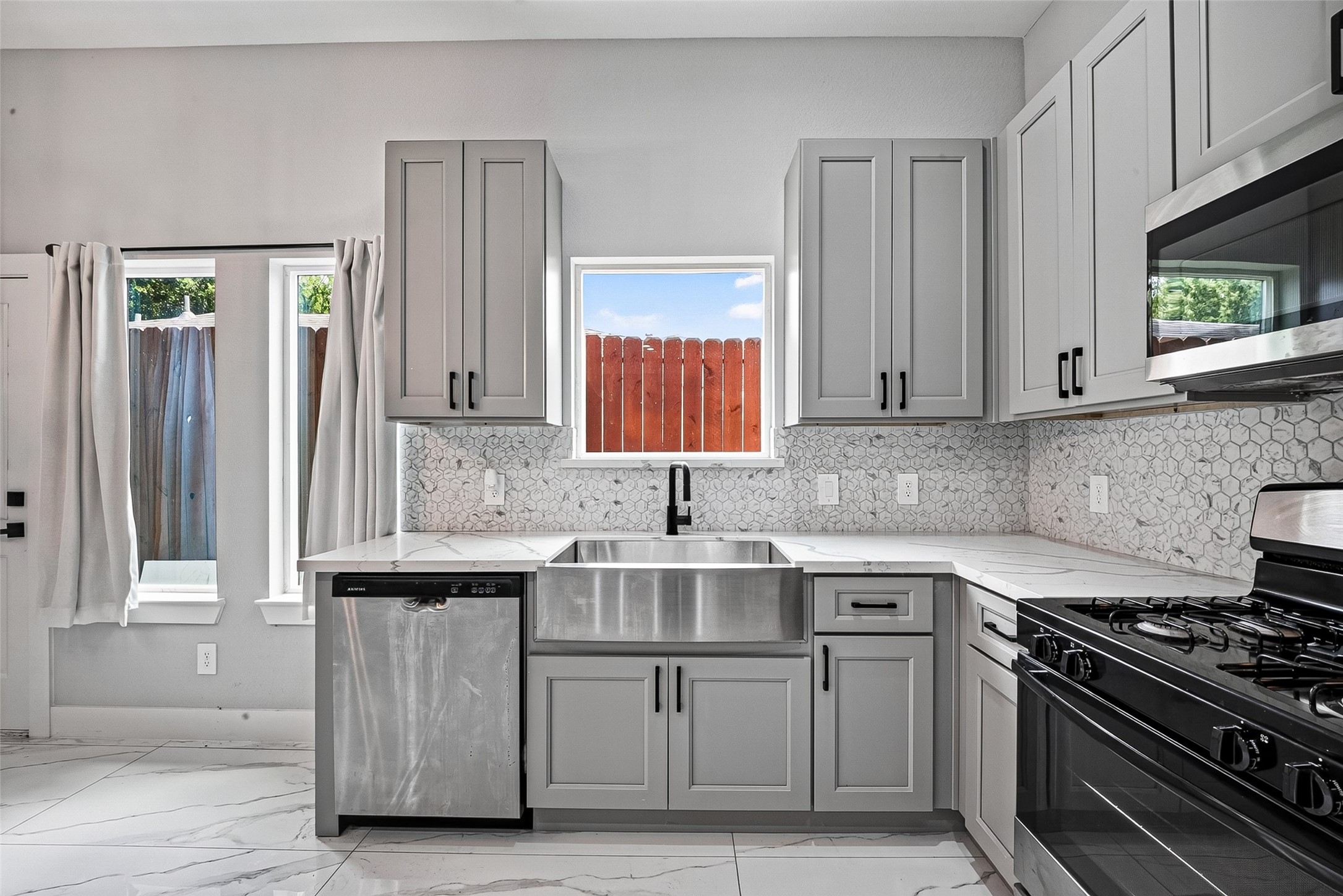 5027 Dickens Road, Unit B Houston, TX 77021 - Photo 12 of 24 Stainless steel farmhouse sink with gooseneck faucet beneath a picture window.