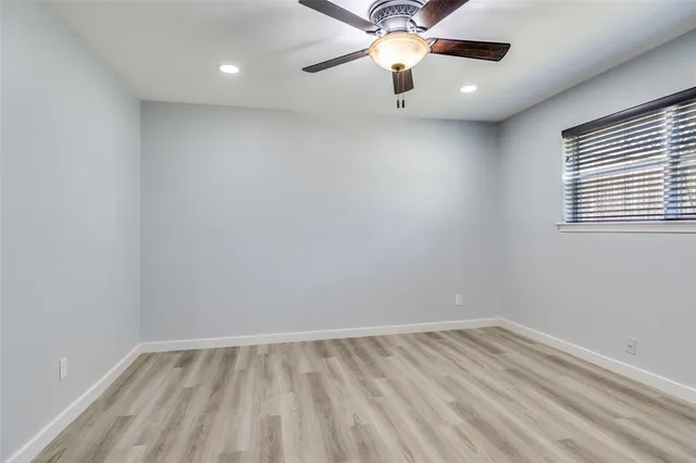 an empty room with a window and a fan