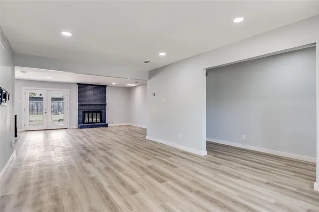 a view of empty room with wooden floor and kitchen view
