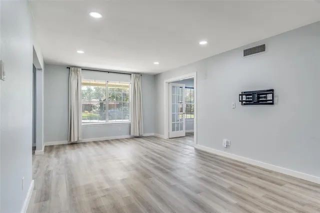a view of an empty room with wooden floor and a window