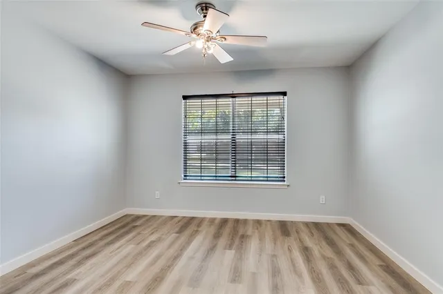 an empty room with a window and a ceiling fan