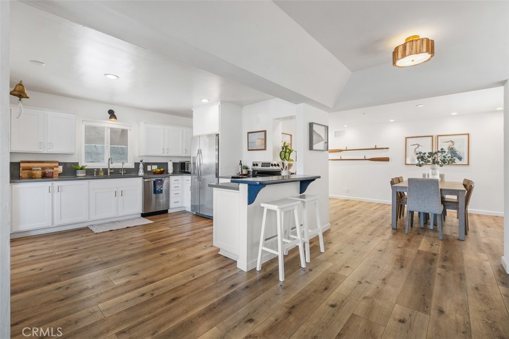 3810 Channel Place Newport Beach, CA 92663 - Photo 16 of 43 a kitchen with stainless steel appliances granite countertop dining table chairs and wooden floor