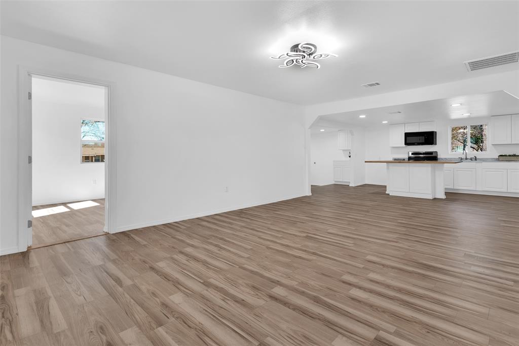 909 East Sears Street Denison, TX 75021 - Photo 10 of 24 Unfurnished living room featuring dark wood-type flooring and baseboards