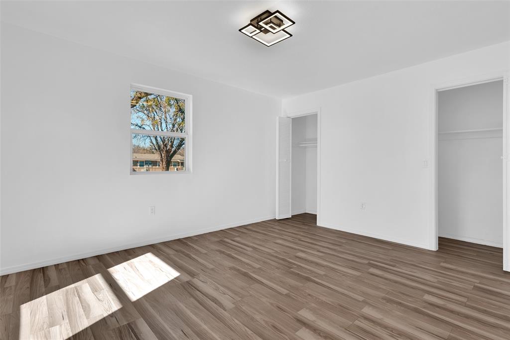 909 East Sears Street Denison, TX 75021 - Photo 13 of 24 Unfurnished bedroom featuring wood finished floors and two closets