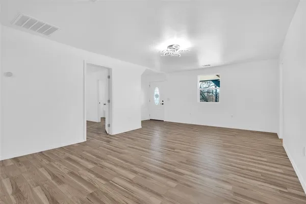 an empty room with wooden floor and window