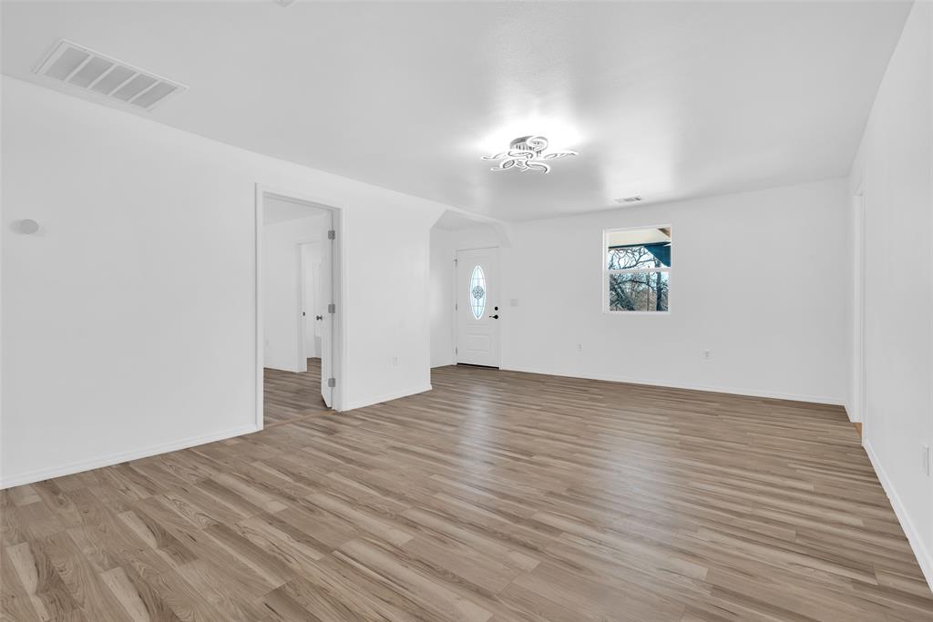 909 East Sears Street Denison, TX 75021 - Photo 8 of 24 Empty room featuring light wood-style floors and baseboards